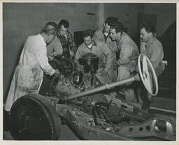 Class of students watch an instructor work on a car radiator, ca. 1949