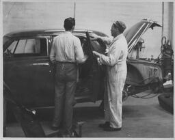 Two students look at a car with hood open