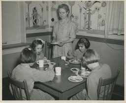 Children at a table with nurse watching