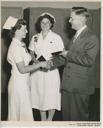 Administrator shakes hands and passes a diploma to a graduating student, ca. 1952