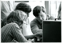 Three students looking closely at a machine