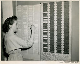 Person puts a punch card in a holder on the wall, ca. 1952