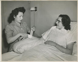 Student nurse wrapping patient's wrist with a bandage