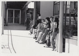 Students leaning against a wall in VCC Courtyard