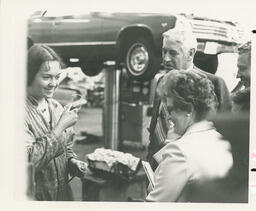 Student speaks to visitors in the auto shop