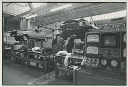 Students work under cars in an auto shop