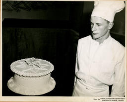Student looking at a cake, ca. 1951