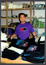 Student standing behind a table of folded shirts