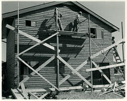 Students on scaffolding working on side of house