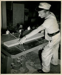 Carpentry student sawing a piece of wood, ca. 1950