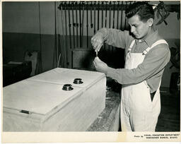 Student using a screwdriver on a kitchen cabinet, ca. 1956