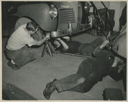 Students working under cars in auto shop, ca. 1949