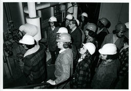 Engineering students on a tour, looking at a machine, c1. 1976