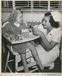 Nurse helping child in high chair, ca. 1952