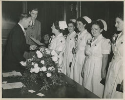 Nursing students standing in a line to receive diplomas