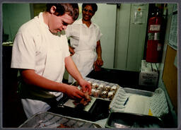 Student packaging food in kitchen