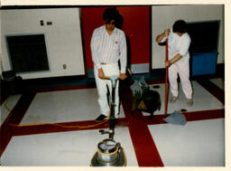 Two students mop and wax a floor