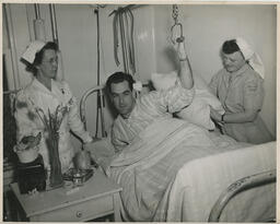 Student nurse helping patient holding strap from ceiling