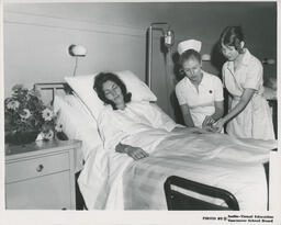 Nurses attending to person in hospital bed