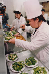 Student chefs plating salad in a kitchen