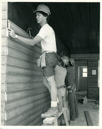 Students building a wooden wall inside a house