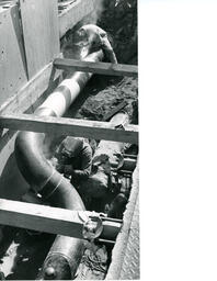 Two students welding a large pipe in the ground, ca. 1972