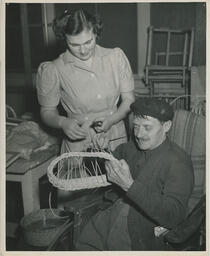 Nursing student helps an elderly veteran do basket-weaving