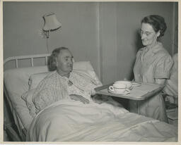 Nursing student serving a meal to a patient