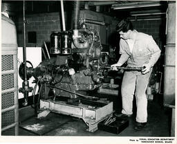 A student uses a tool to adjust a diesel engine, ca. 1967