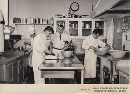 Culinary instructor watches students cook in kitchen, ca. 1959