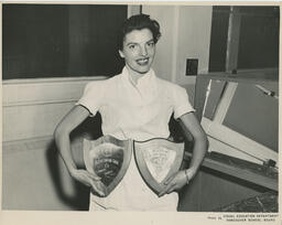 Beauty Culture student holding two plaques, ca. 1954