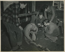Plumbing students watch instructor work on pipe, ca. 1949