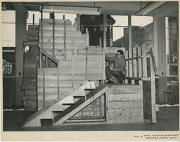 Student crouched on a half-completed stair structure, ca. 1960