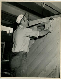 Student hammering wood slats on a wall, ca. 1949