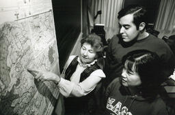 Teacher pointing at map while students look on