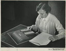 Person typing on machine, ca. 1957