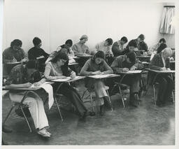Students writing at desks in a classroom