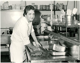 Student washing dishes in an industrial sink