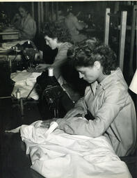 Students sewing large pieces of white fabric