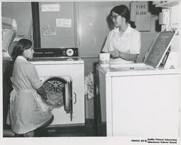 Two students in the Family Aide program at washer and dryer