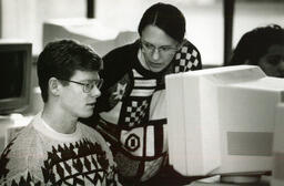 Two people in front of a large computer monitor