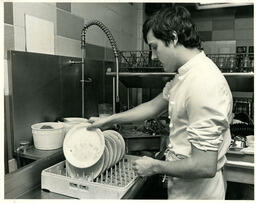 Student stacks dishes in a dishwashing area