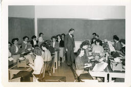 Instructor in a class full of students at typewriters