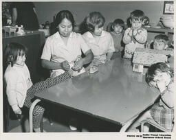 Two students in the Family Aide program at a table with preschoolers