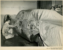 Students taping newspaper on a car to protect it, ca. 1960