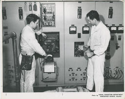 Students at a wall of electronic radio equipment, ca. 1966