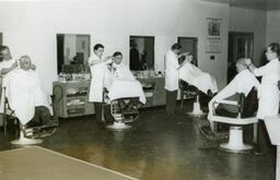 Four barbering students giving haircuts to customers