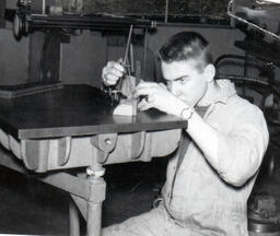 Student looking closely at a toggle device, ca. 1962