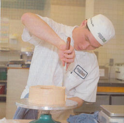 Baking student icing a cake