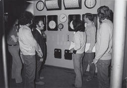 Students on a tour looking at a machine with gauges